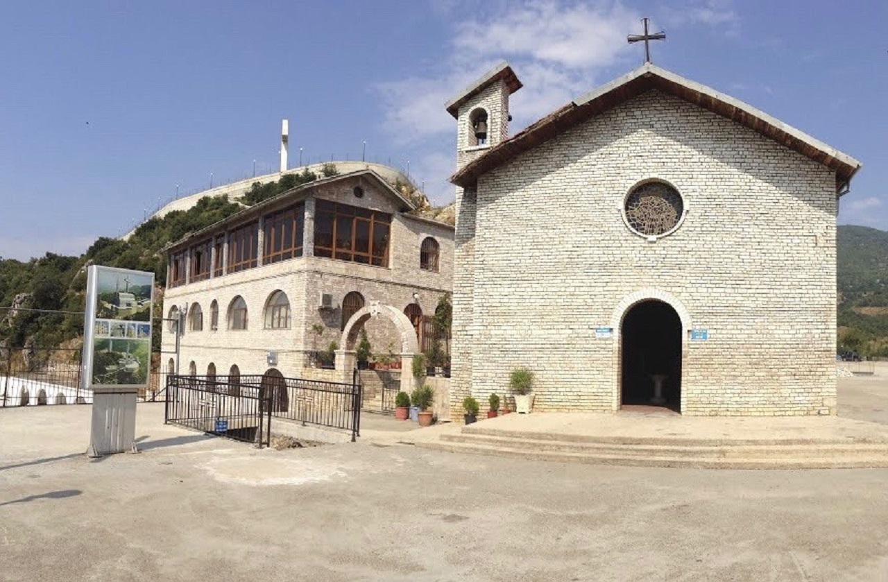 Church courtyard and green hills above Lac